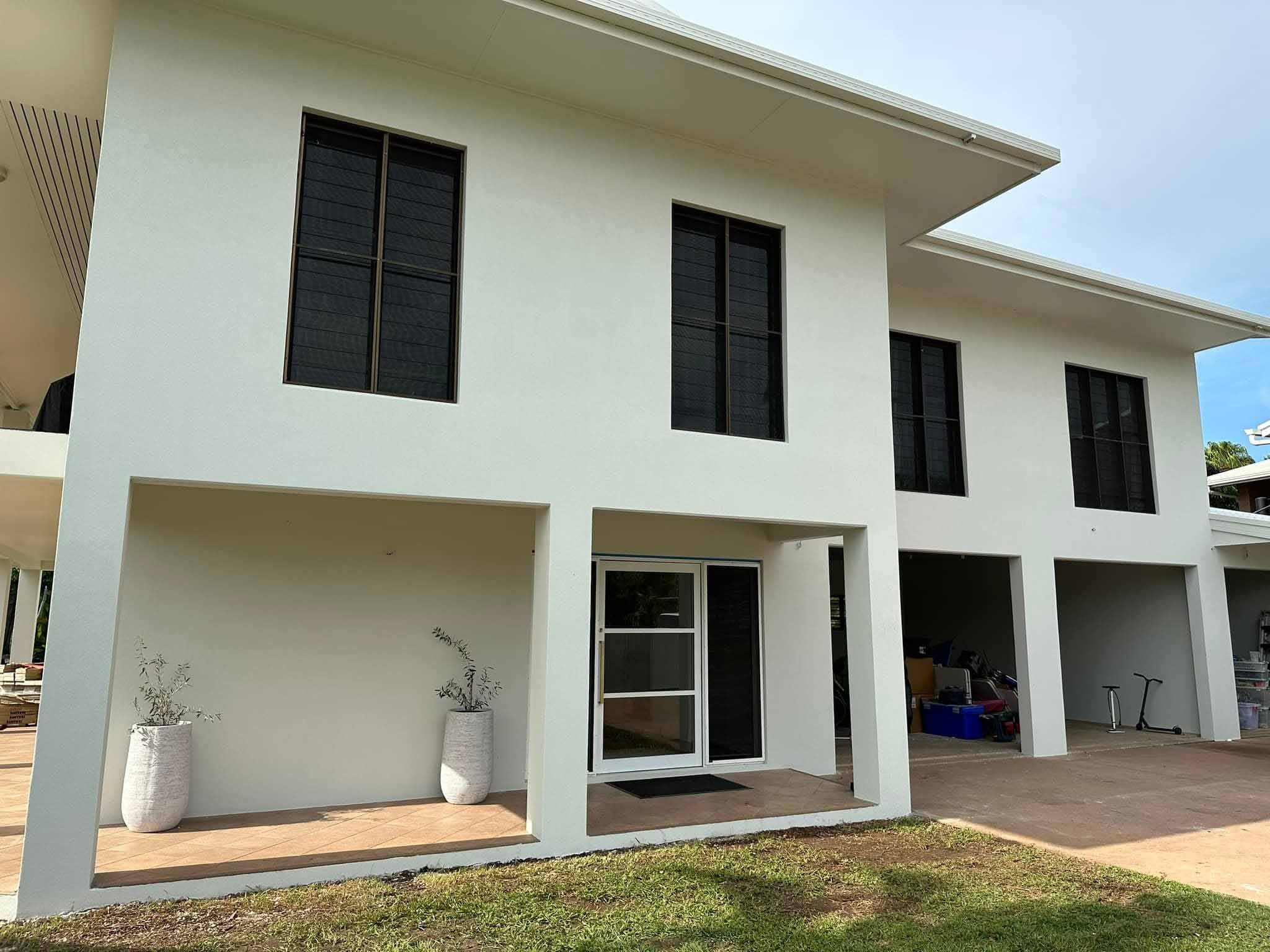 Rear of a two-storey house with smooth white rendered walls and a covered patio