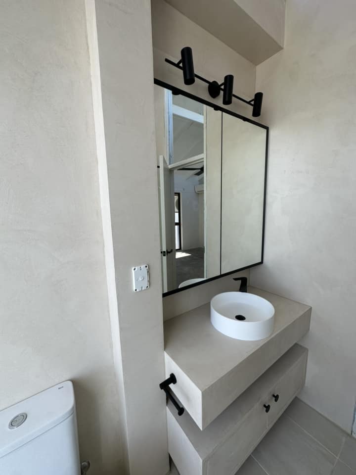 Bathroom with a seamless beige vanity and walls, round basin and black-framed mirror