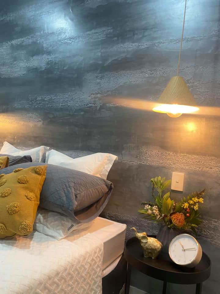 Bedroom with a dark grey metallic plaster feature wall and a pendant light