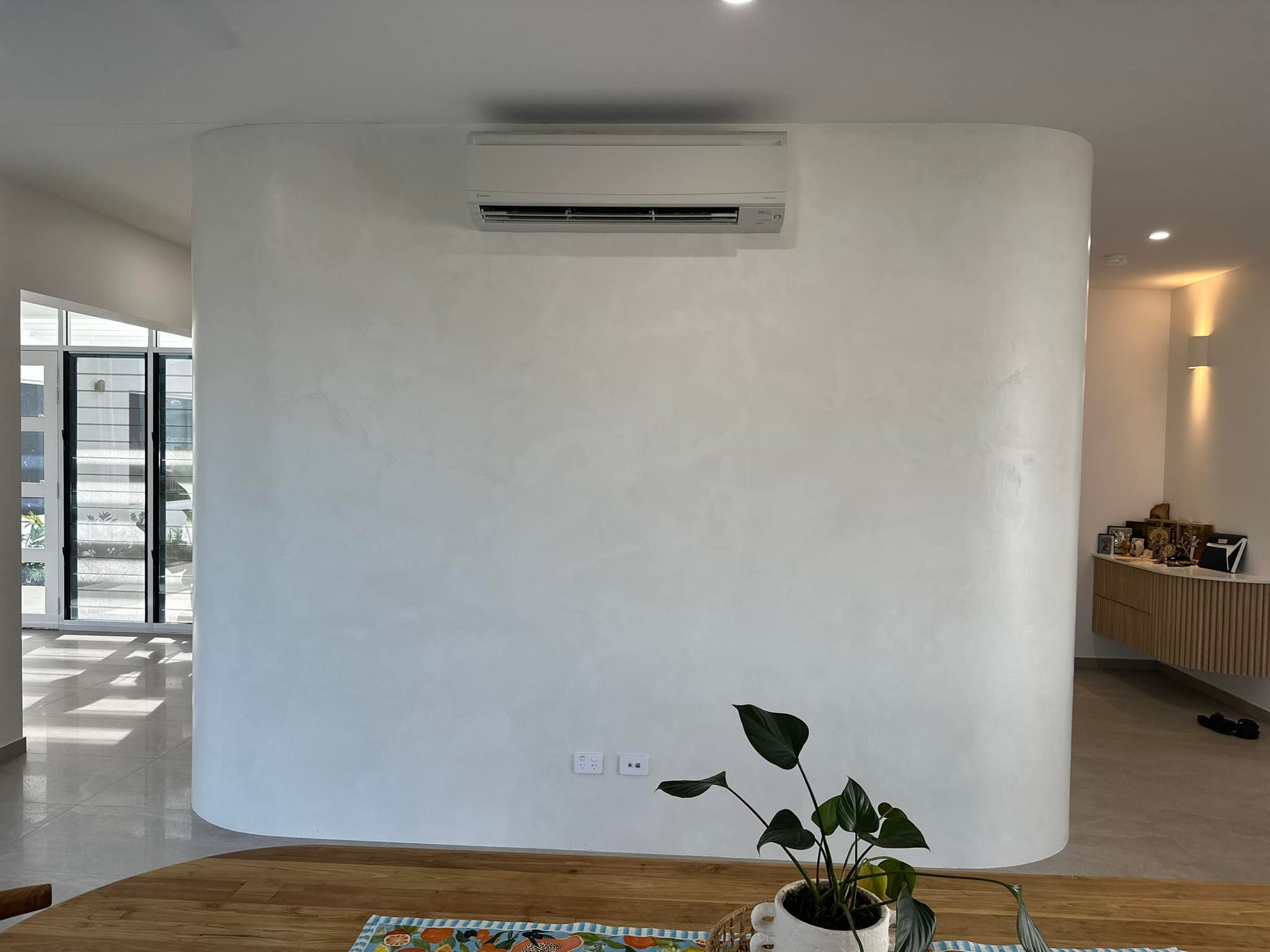 Curved freestanding wall with a smooth white finish and a split-system air conditioner