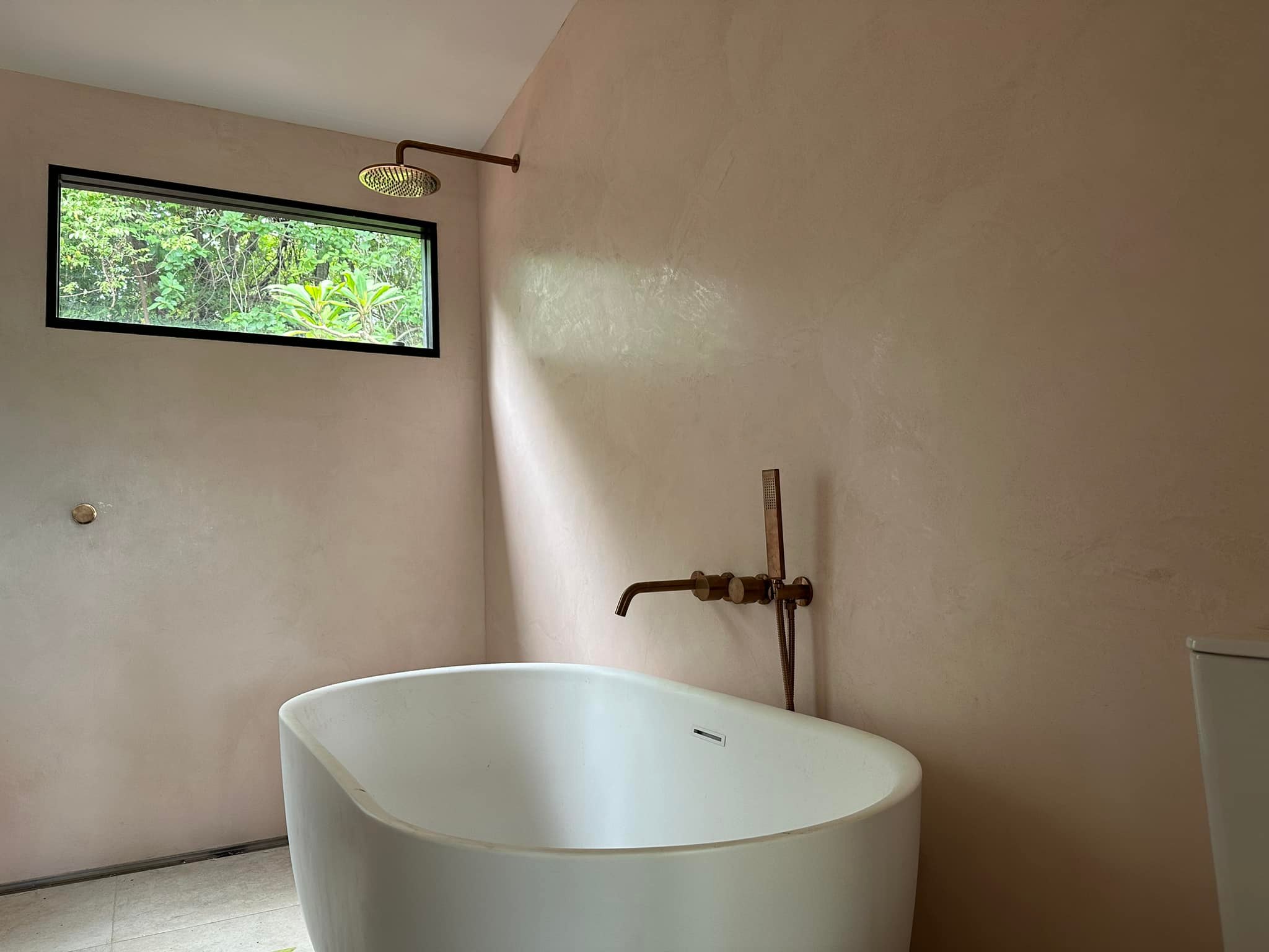 Bathroom with blush pink seamless walls, a freestanding bath and copper tapware