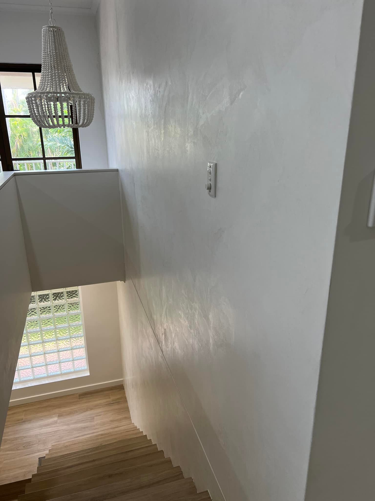 Stairwell wall with a smooth white finish and a beaded pendant light