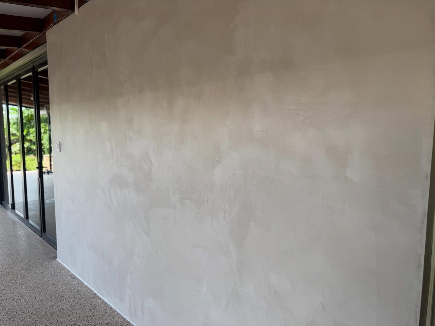 Large smooth beige wall finish beside glass sliding doors