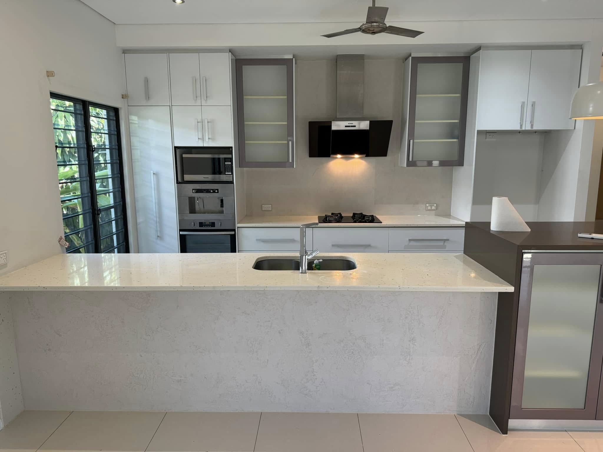 Kitchen with white cabinets and a pale stone-look island bench with a double sink