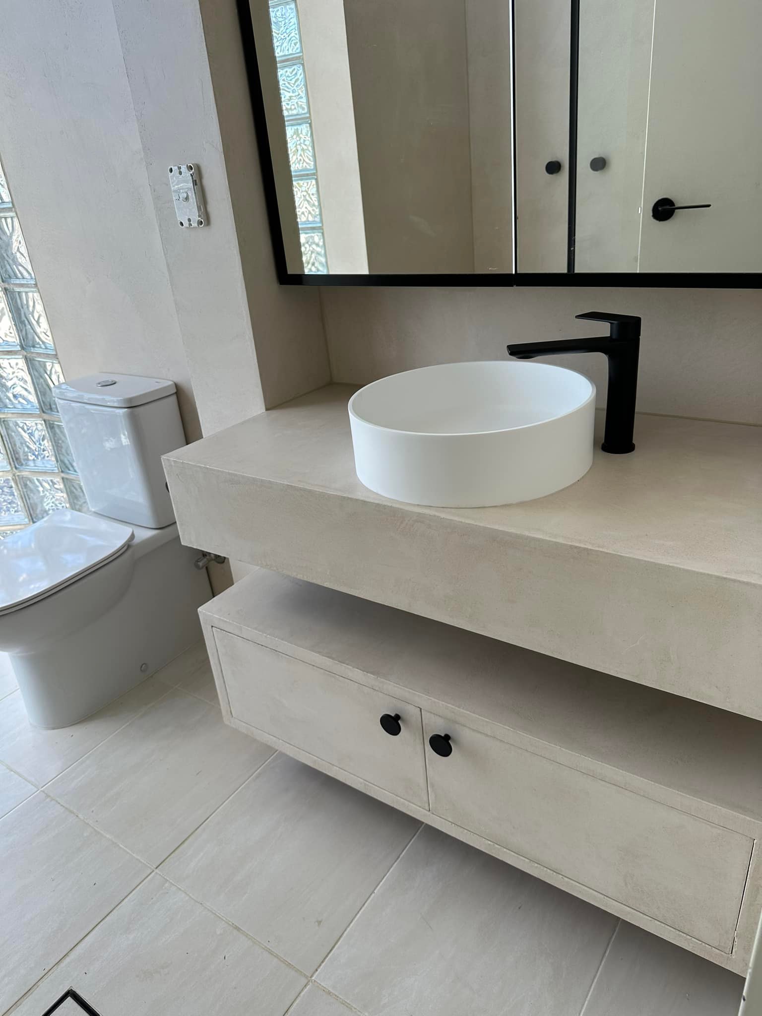 Floating beige vanity with two drawers, a round basin and black tapware