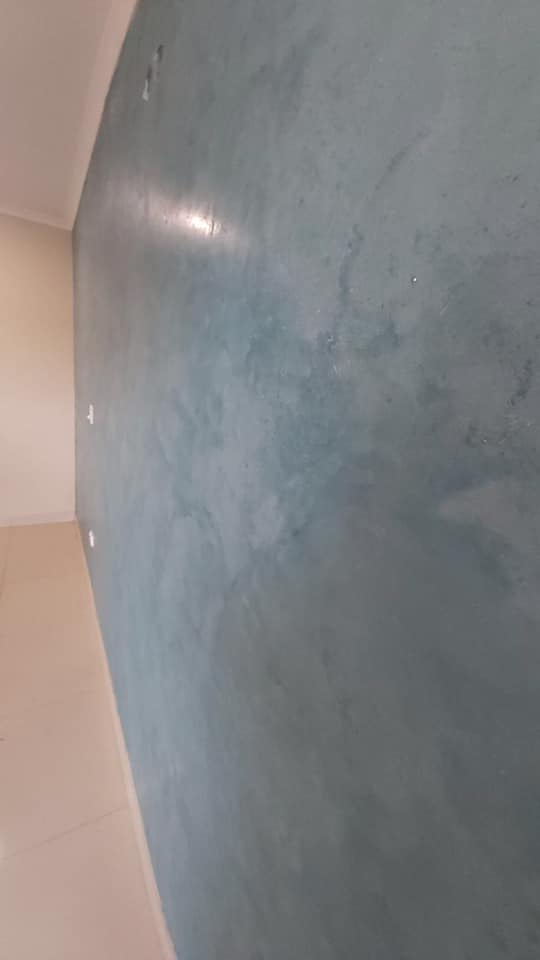 Teal blue polished plaster wall along a long room