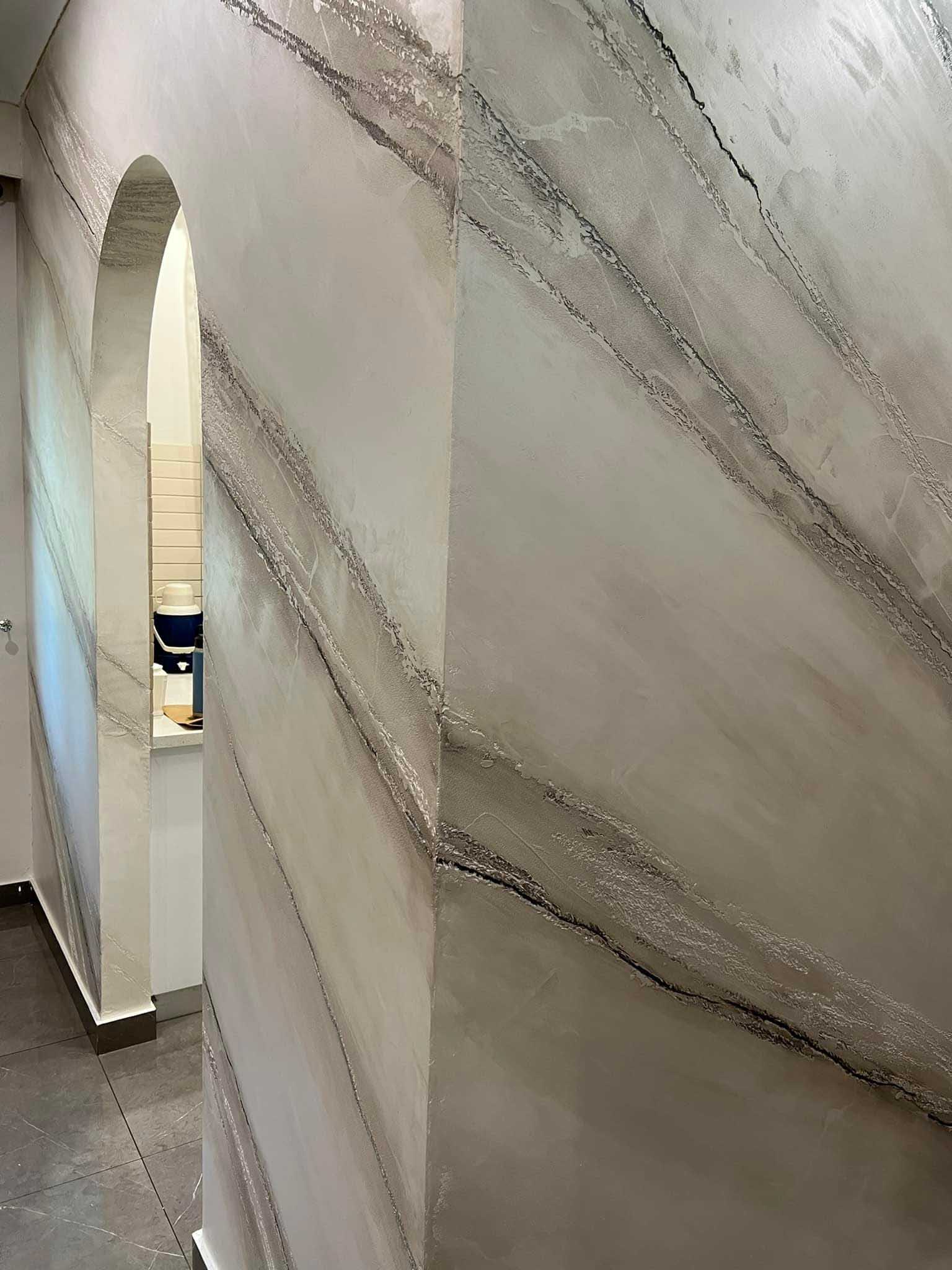 Marble-effect plaster walls with grey veining beside an arched doorway