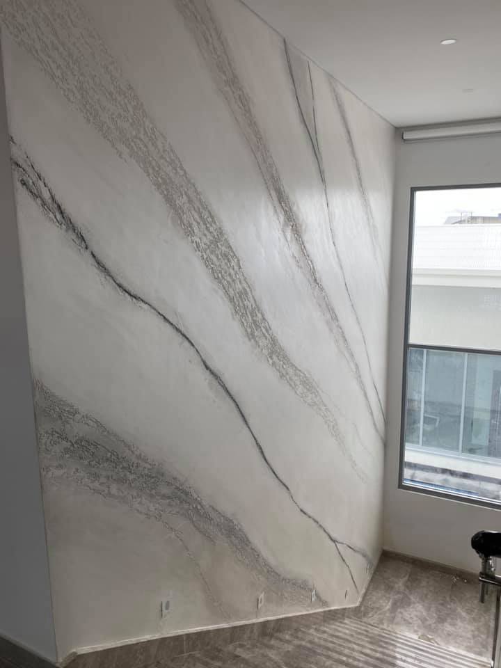 Tall wall with a white marble-effect plaster finish and dark veining