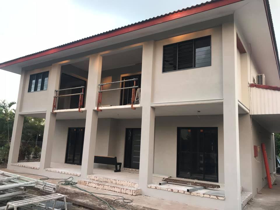 Two-storey house with freshly rendered pale grey walls and balconies