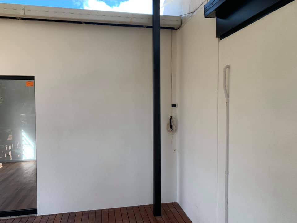 White rendered exterior walls on a timber deck beside a black post