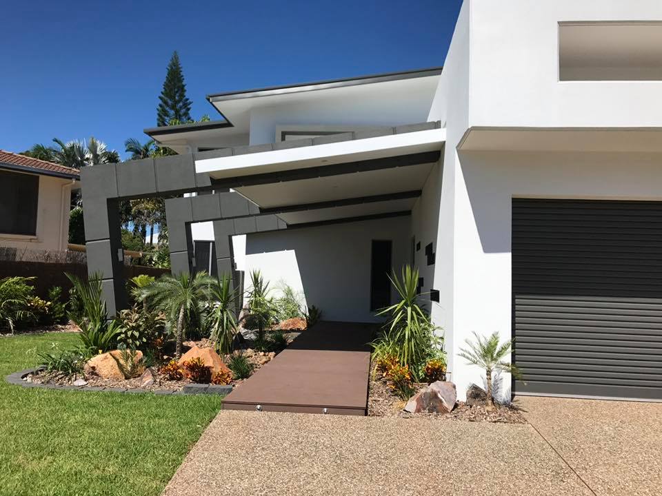 Modern white rendered house entry with a landscaped garden and dark garage door