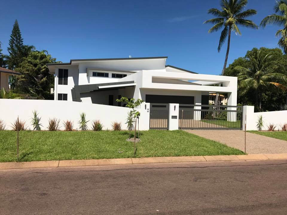 Modern white rendered house and front fence behind a green lawn
