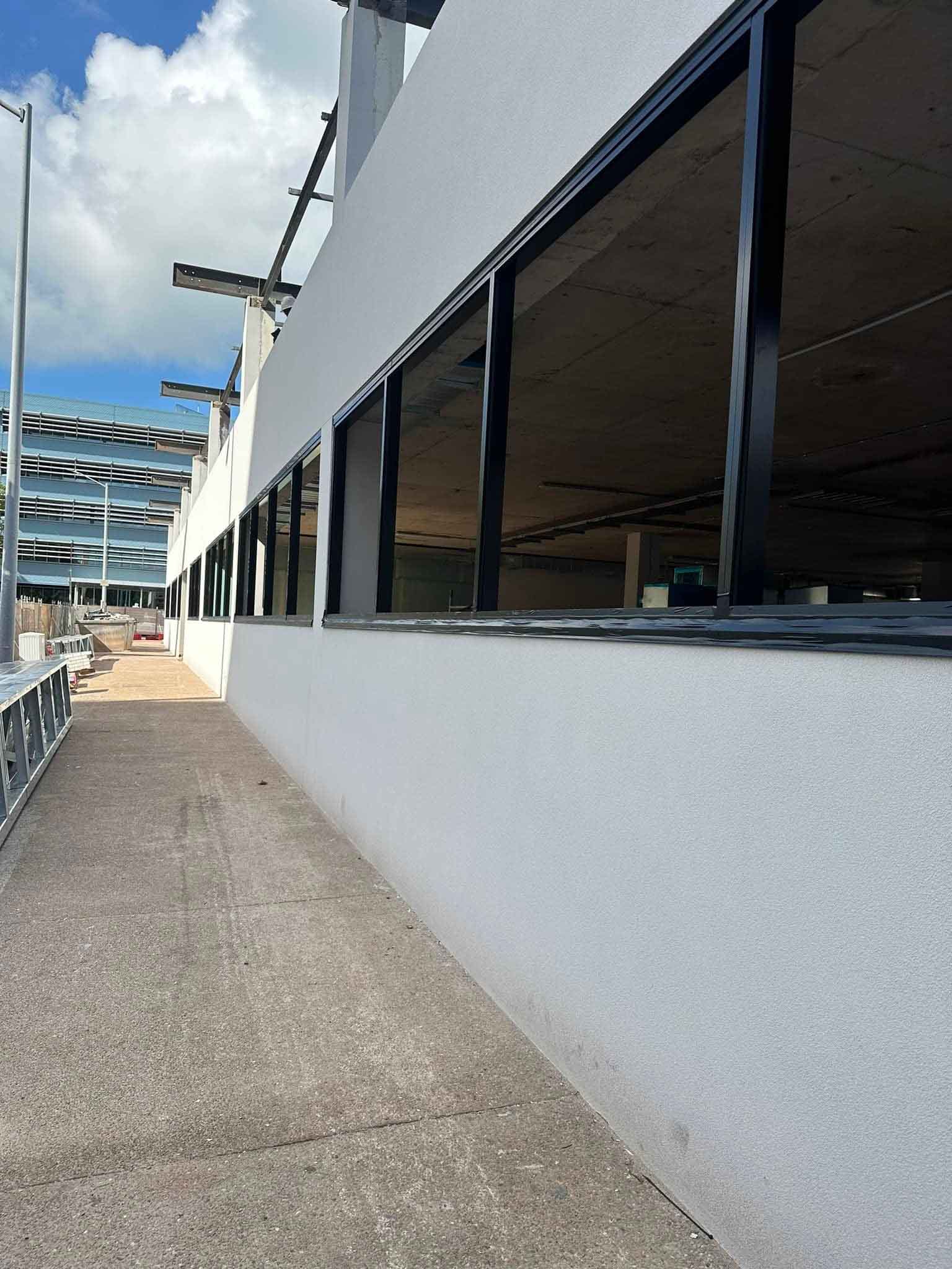 Long white rendered exterior wall beside a concrete path