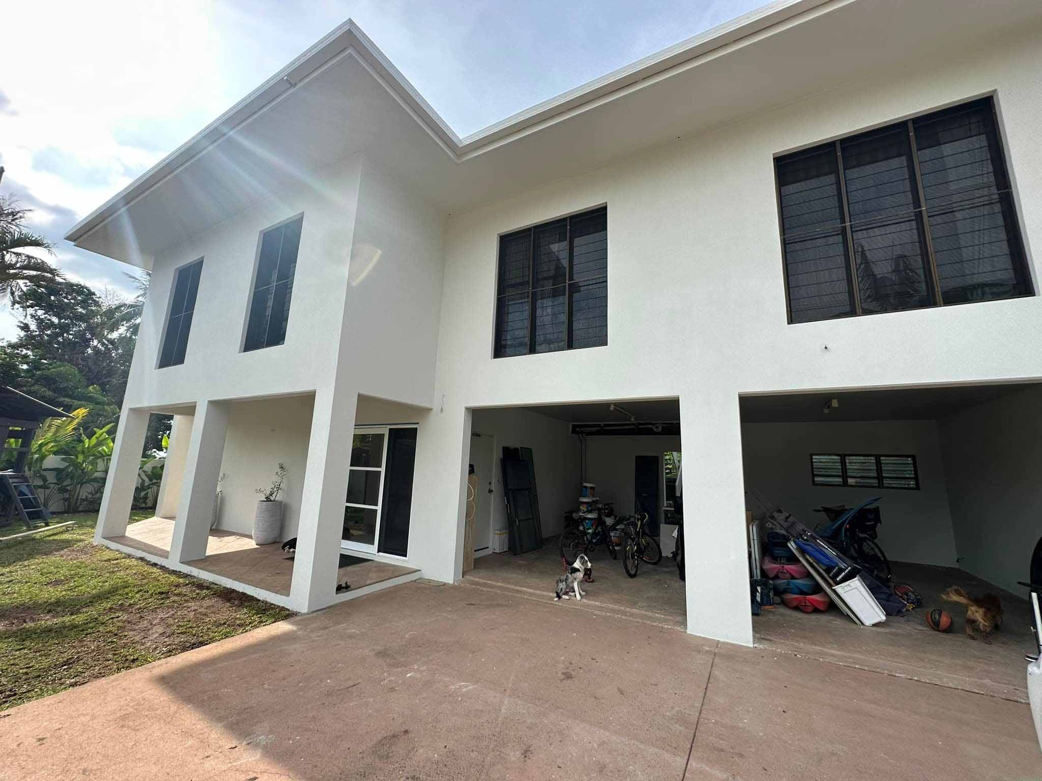 Two-storey house with white rendered walls and an open garage underneath