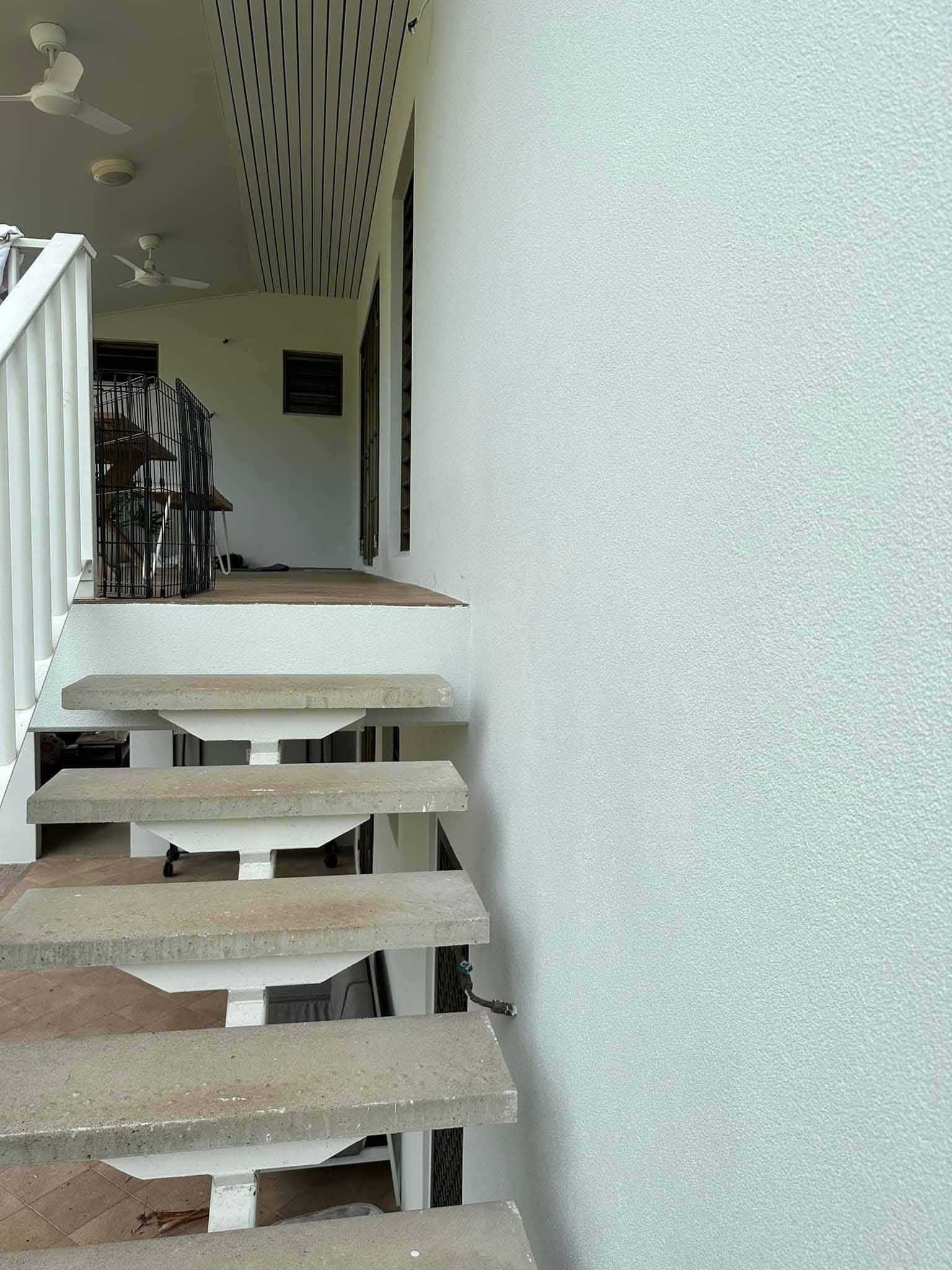 White rendered wall beside open outdoor stairs