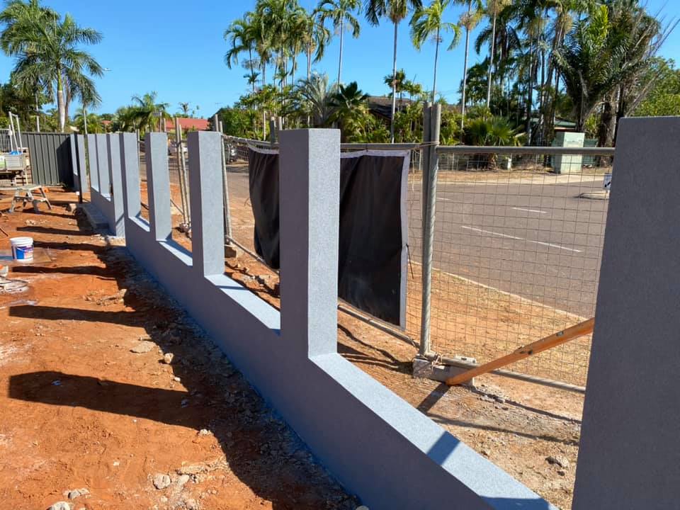 New grey rendered front fence wall and pillars beside a street