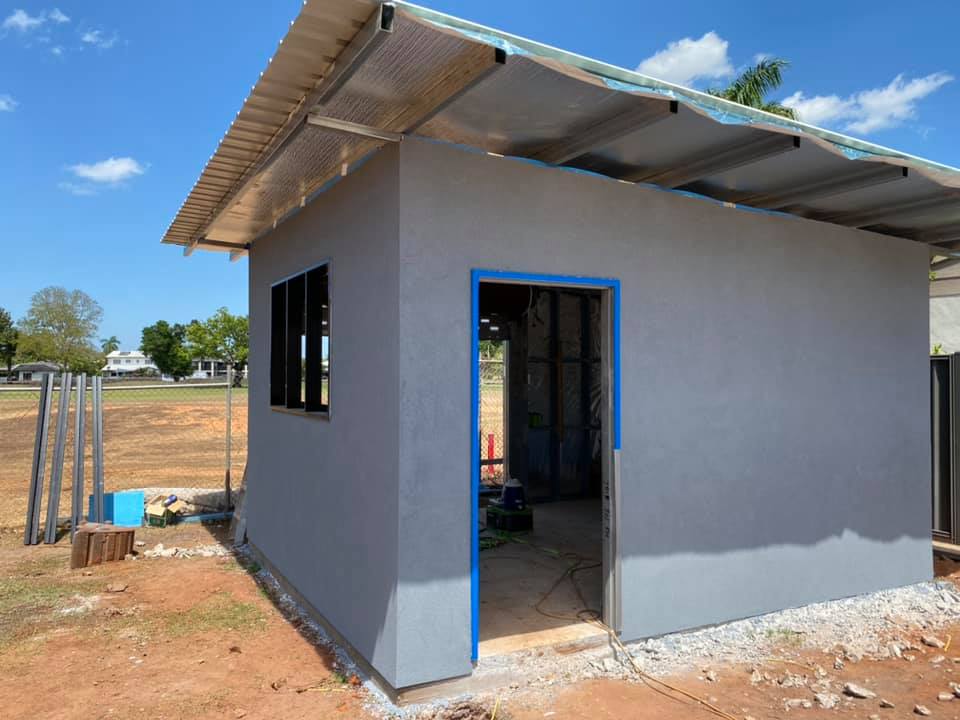 Small building with fresh grey render and an open doorway under a new roof
