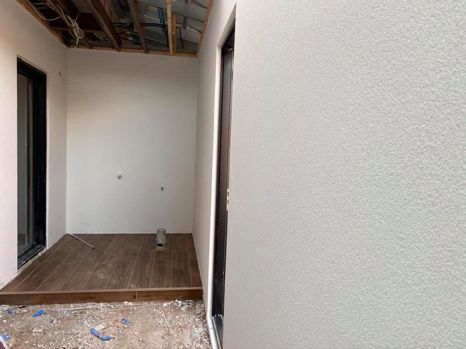 Unfinished outdoor room with smooth white rendered walls and an open ceiling