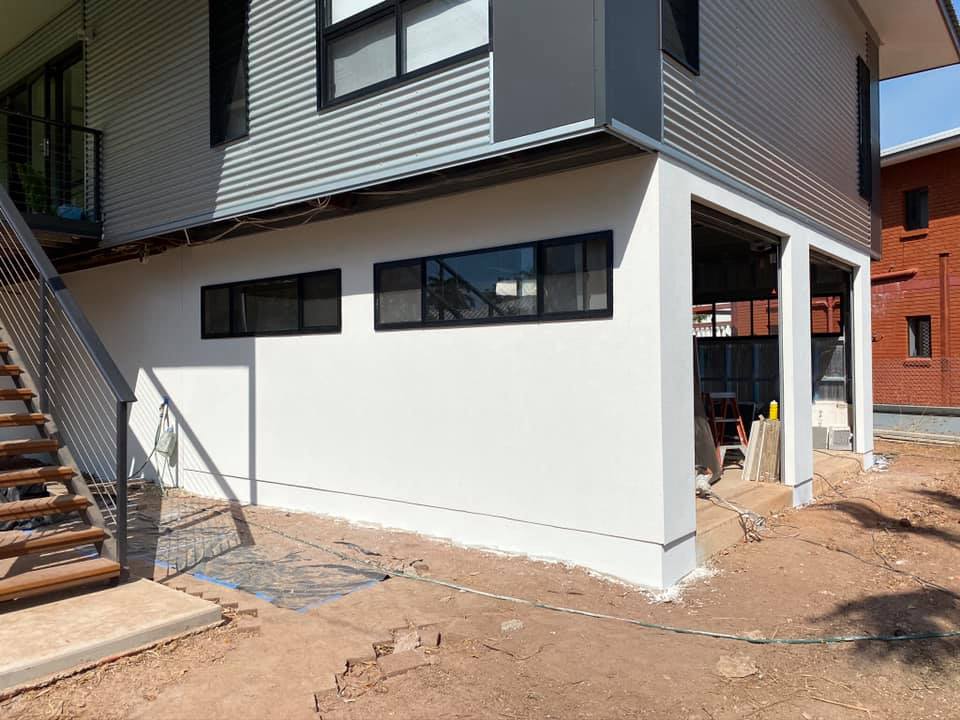 White rendered ground floor of a two-storey house with grey cladding above