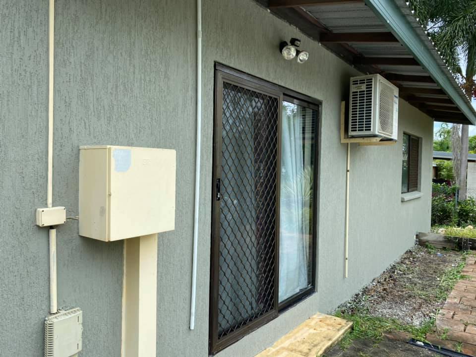 Grey textured rendered house wall with a sliding door and air conditioner