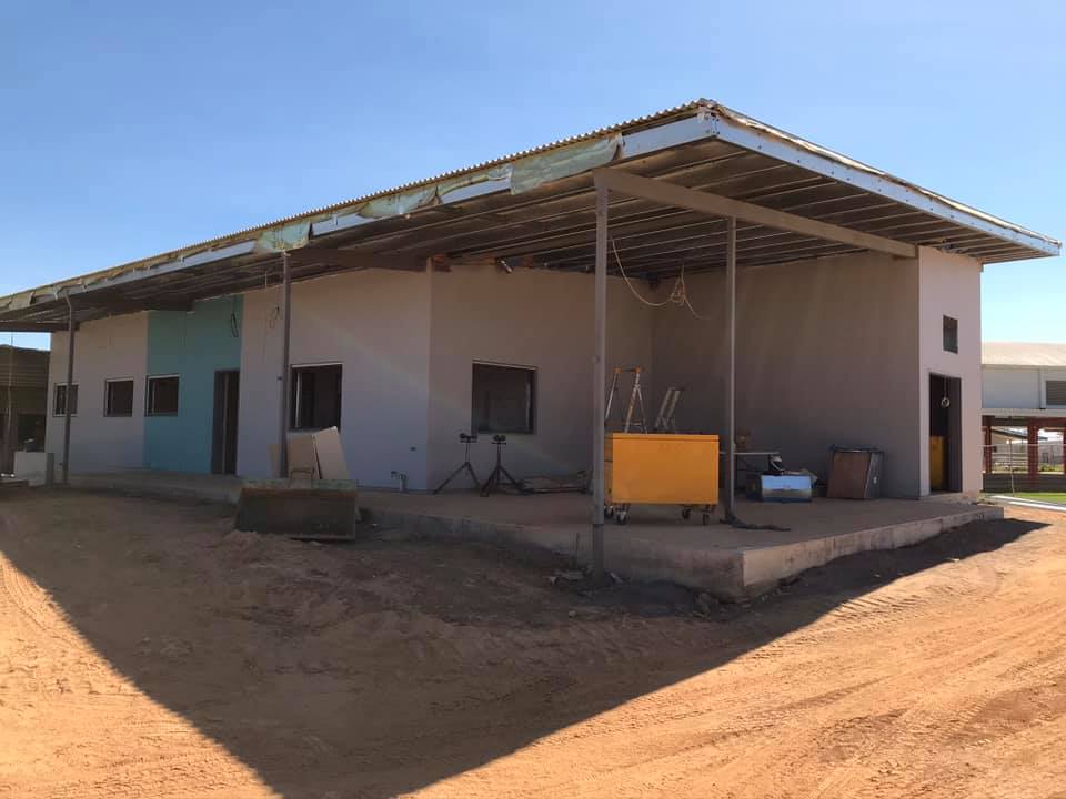 Single-storey building with fresh render under a large steel awning