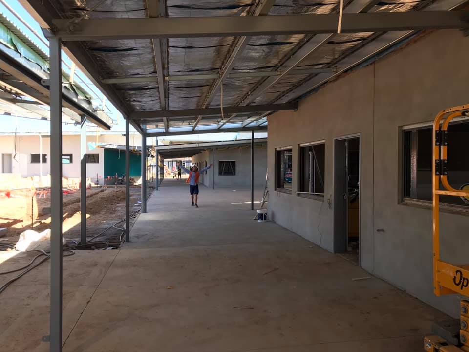 Covered walkway beside a grey rendered building under construction