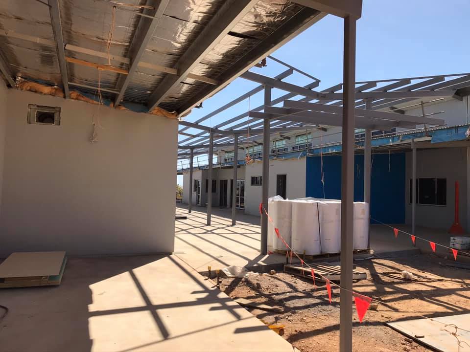 Grey rendered wall under a steel-framed roof on a building site