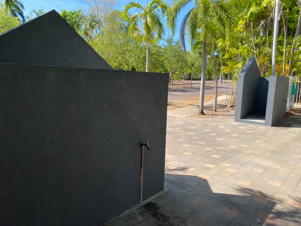 After: the same outdoor wall structure repaired and rendered dark grey