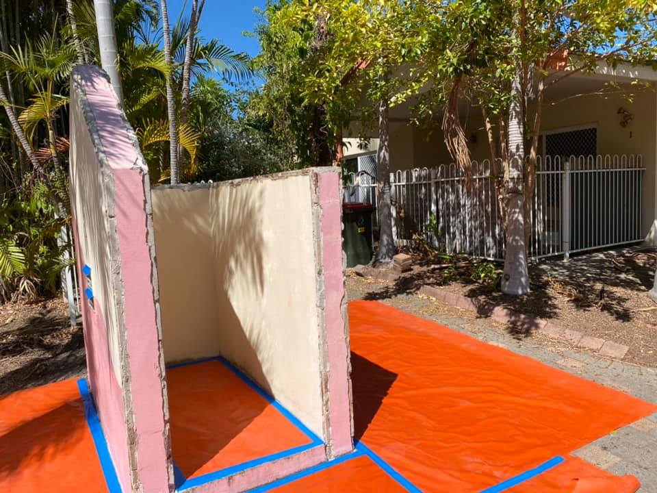 Before: patchy pink and beige walls of an outdoor structure on an orange drop sheet